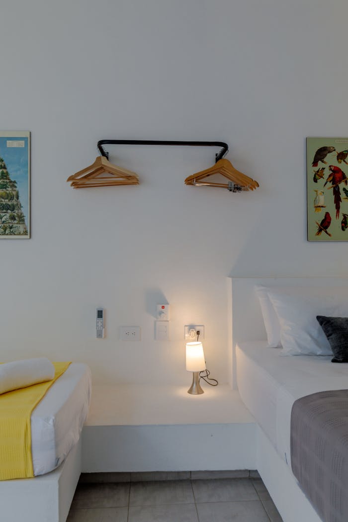 A simple and elegant hotel room with a modern aesthetic featuring a bed, wall art, and ambient lighting.