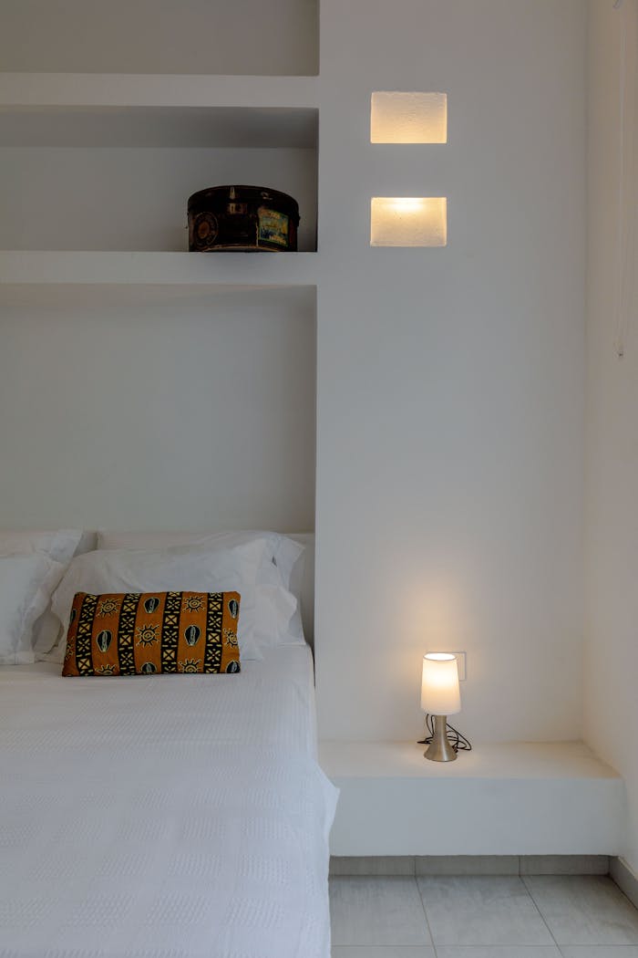 A serene, minimalist bedroom interior with white walls and cozy decor.